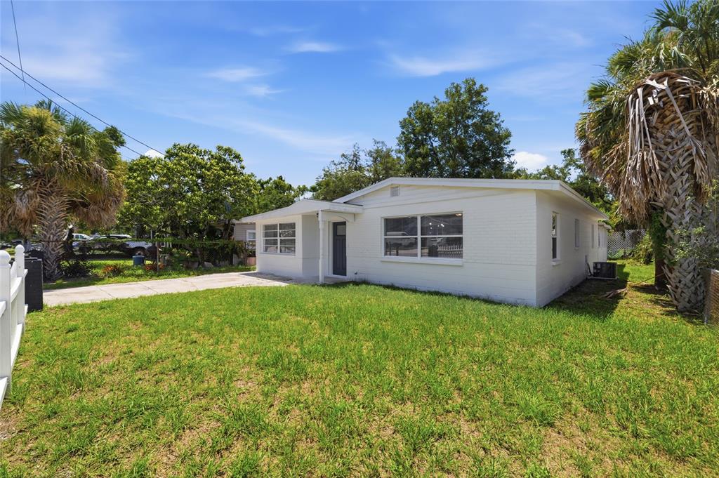 A white, single-story house with a concrete driveway and a green lawn under a blue sky — 4009 E POWHATAN AVENUE, TAMPA, FL