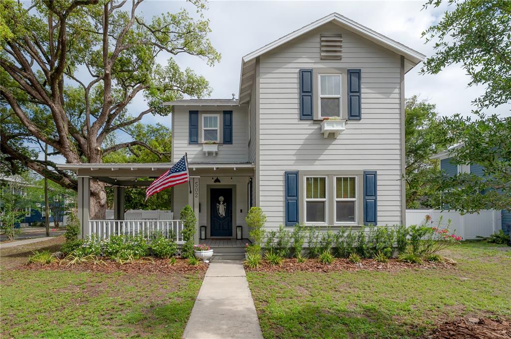 A two-story house with light gray siding, blue shutters, and a front porch with a flag — 502 E AMELIA AVENUE, TAMPA, FL