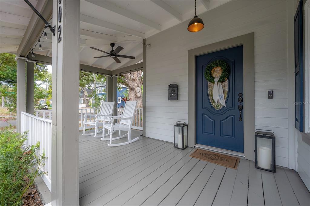A covered front porch features a blue door, two white rocking chairs, and gray flooring — 502 E AMELIA AVENUE, TAMPA, FL