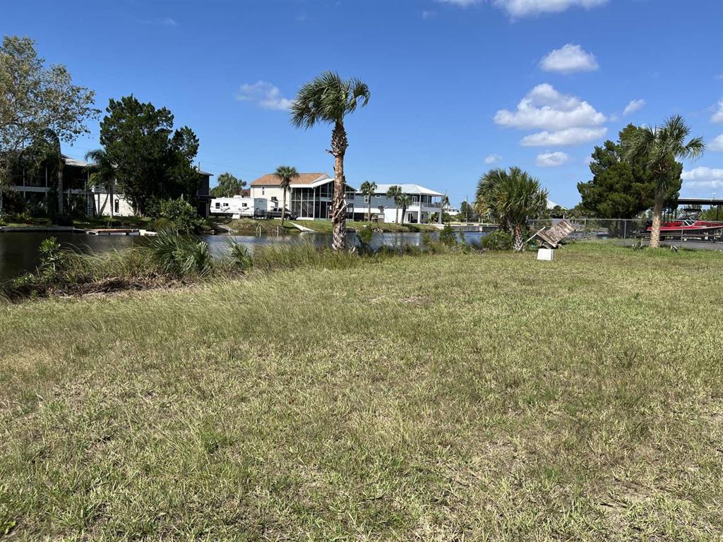 A grassy waterfront lot features a palm tree and views of neighboring houses and boats — 3341 SHOAL LINE BOULEVARD, HERNANDO BEACH, FL