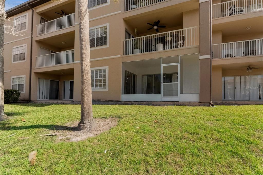 The exterior of a multi-story apartment building features a screened-in ground floor patio — 14036 FAIRWAY ISLAND DR UNIT 1513, ORLANDO, FL
