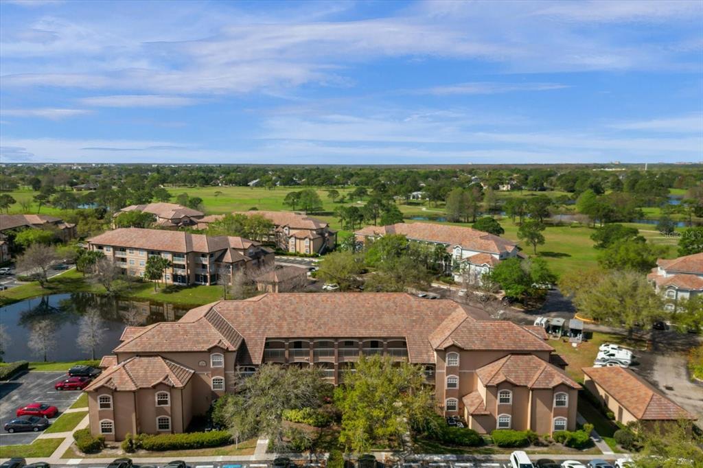 An aerial view shows a multi-story apartment complex surrounded by a golf course and trees — 14036 FAIRWAY ISLAND DR UNIT 1513, ORLANDO, FL