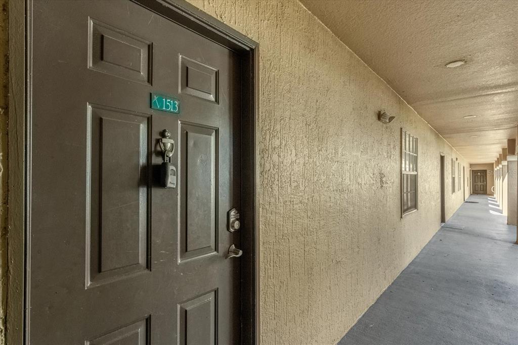 A brown apartment door with a lockbox and unit number 1513 in an exterior hallway — 14036 FAIRWAY ISLAND DR UNIT 1513, ORLANDO, FL