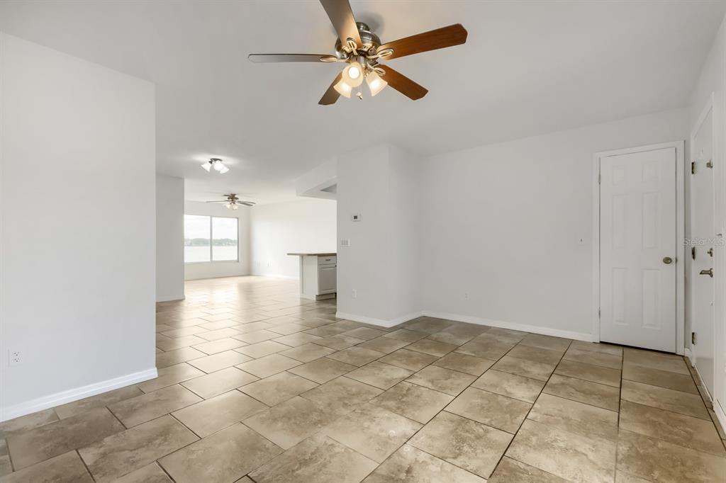 A tiled room with a ceiling fan leads to an open kitchen and living area — 1962 SOCIETY DRIVE, HOLIDAY, FL