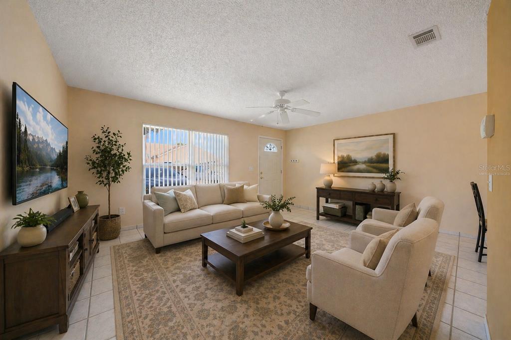 A living room with a sofa, two armchairs, a coffee table, and a television — 67 E COUNTRY COVE WAY, KISSIMMEE, FL