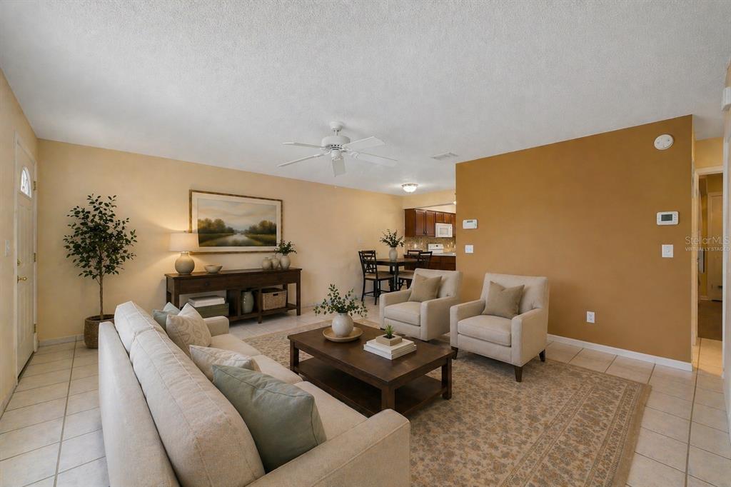 A living room with tile floors, a beige sofa, two armchairs, and a dining area — 67 E COUNTRY COVE WAY, KISSIMMEE, FL
