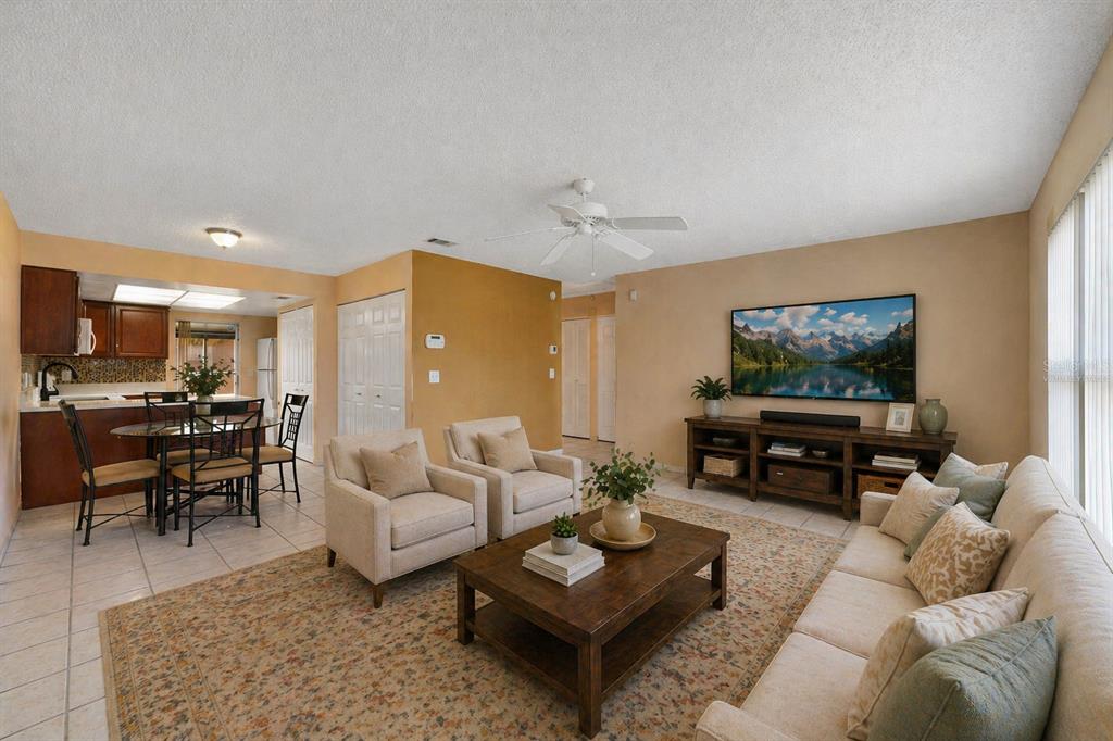 A living room with a beige sofa, two armchairs, a coffee table, and an adjacent kitchen — 67 E COUNTRY COVE WAY, KISSIMMEE, FL