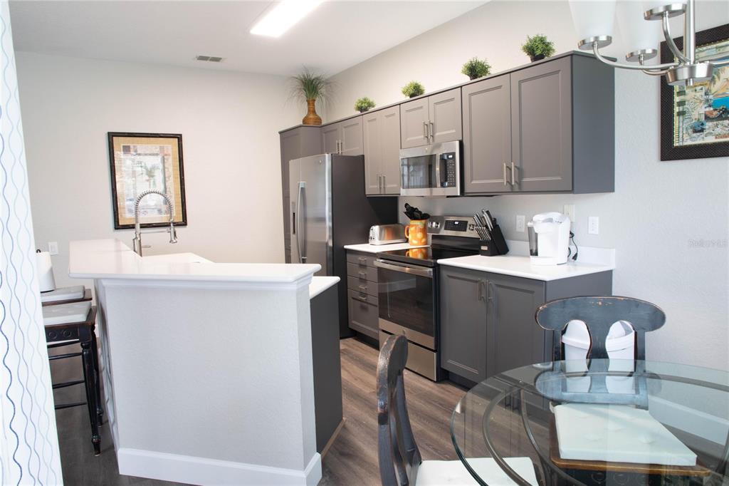 A kitchen features gray cabinets, stainless steel appliances, white countertops, and a breakfast bar — 2648 DINVILLE STREET, KISSIMMEE, FL