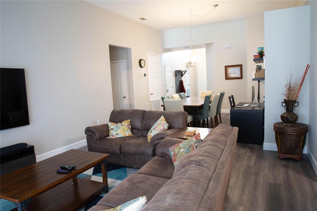 A living room with brown sofas and a coffee table opens to a dining area — 2648 DINVILLE STREET, KISSIMMEE, FL