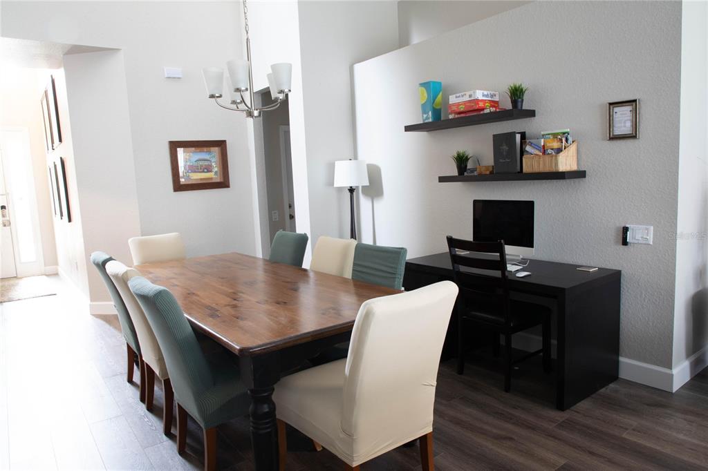 A dining area features a wooden table, mixed chairs, a computer desk, and wall-mounted shelves — 2648 DINVILLE STREET, KISSIMMEE, FL