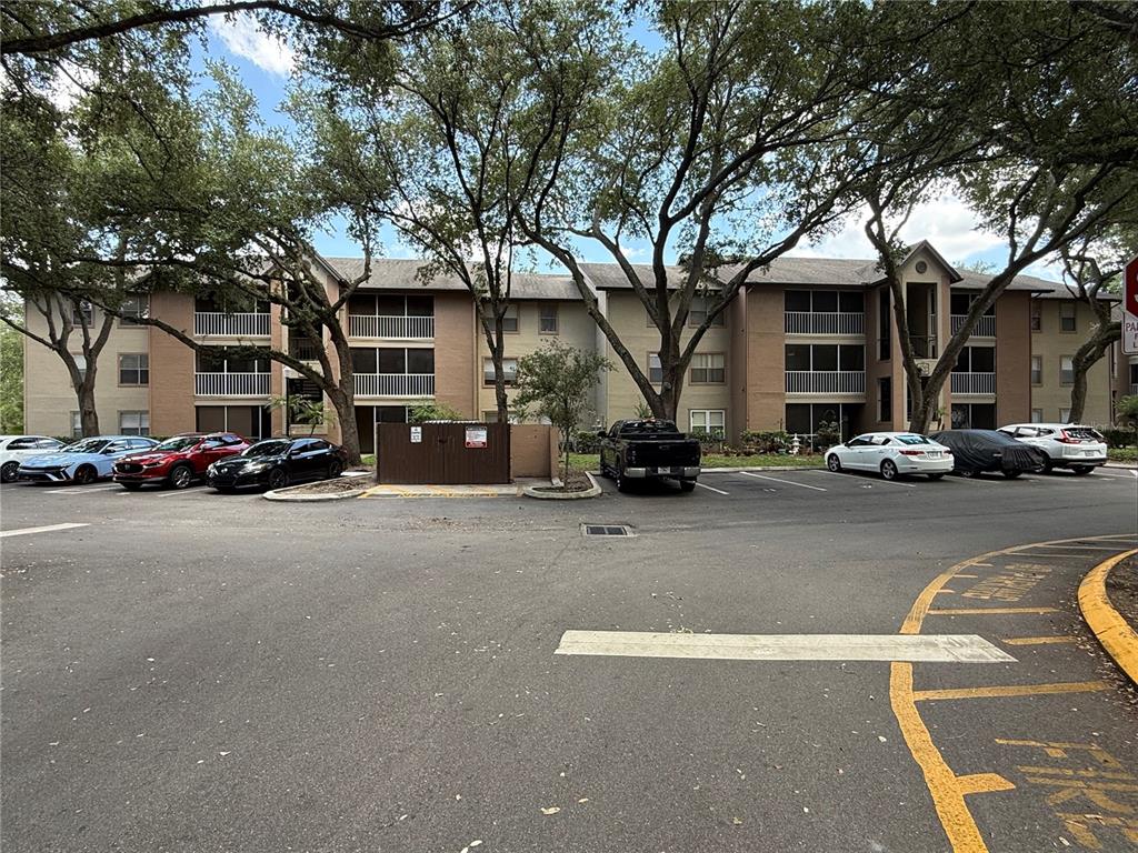 A multi-story apartment building with a parking lot and large trees in front — 956 SALT POND PLACE UNIT 204, ALTAMONTE SPRINGS, FL