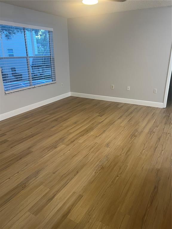 An empty room with light wood-look flooring, gray walls, and a window with white blinds — 956 SALT POND PLACE UNIT 204, ALTAMONTE SPRINGS, FL