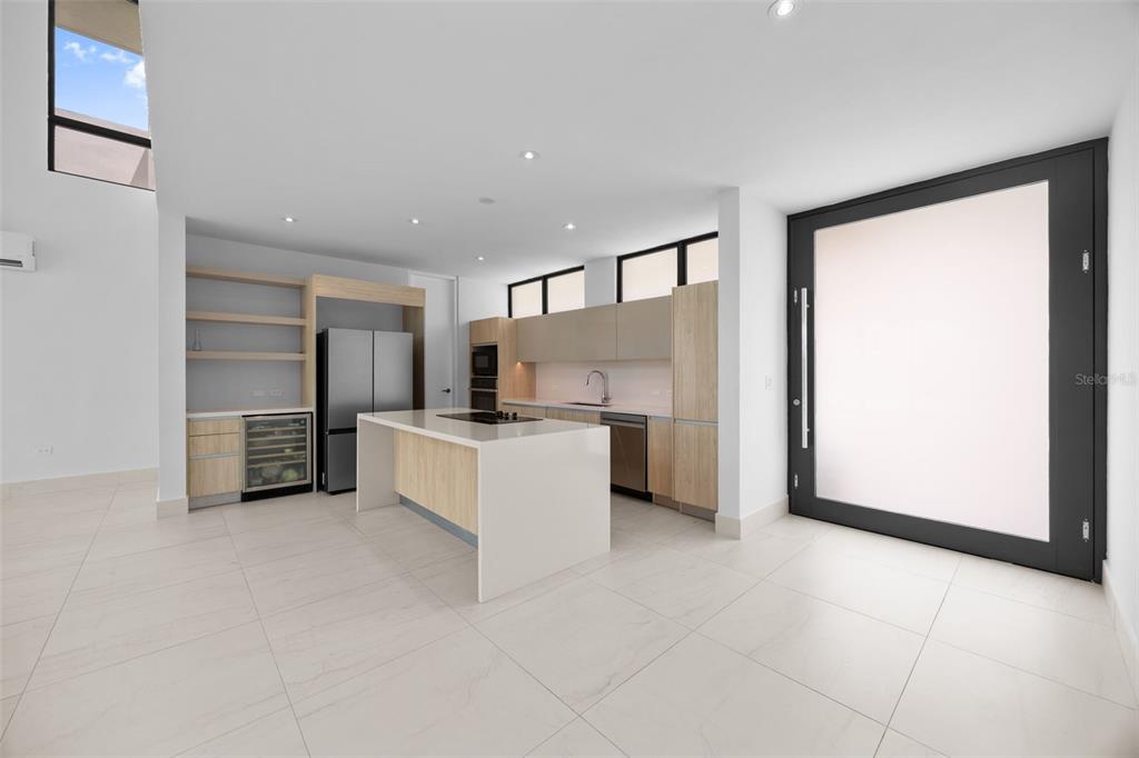 A modern kitchen features light wood cabinetry, a white island, and large glass doors — RIVIERA PARKVIEW 135 SALONGA STREET, BAYAMON, PR