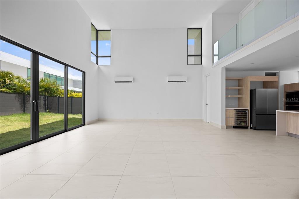 A bright, open-concept living area features high ceilings, white tile floors, and large glass doors — RIVIERA PARKVIEW 135 SALONGA STREET, BAYAMON, PR