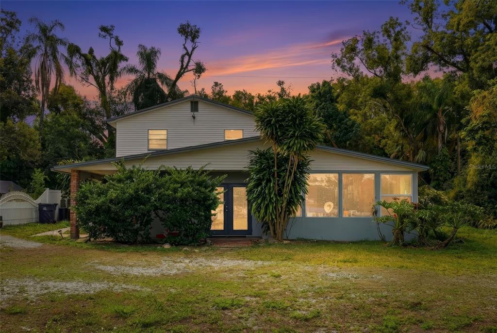 A two-story house with light siding, a sunroom, and a large yard at sunset — 2814 W HUMPHREY STREET, TAMPA, FL