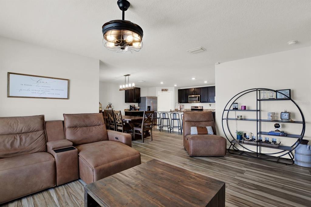A living room with brown leather furniture, a circular metal shelf, and an open kitchen — 1013 TIDAL ROCK AVE, RUSKIN, FL