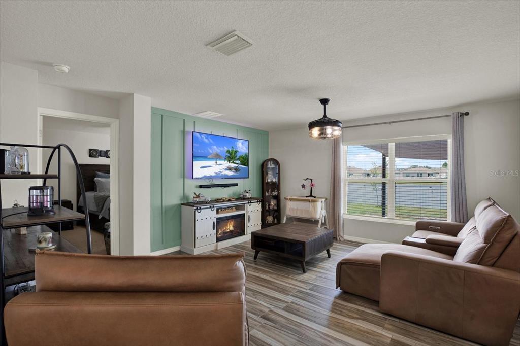 A living room features a green accent wall, a fireplace, and brown leather furniture — 1013 TIDAL ROCK AVE, RUSKIN, FL