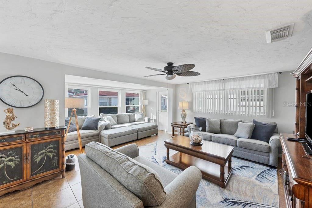 A living room features gray sofas, a wooden coffee table, and a ceiling fan — 6154 MIDNIGHT PASS ROAD UNIT C05, SARASOTA, FL