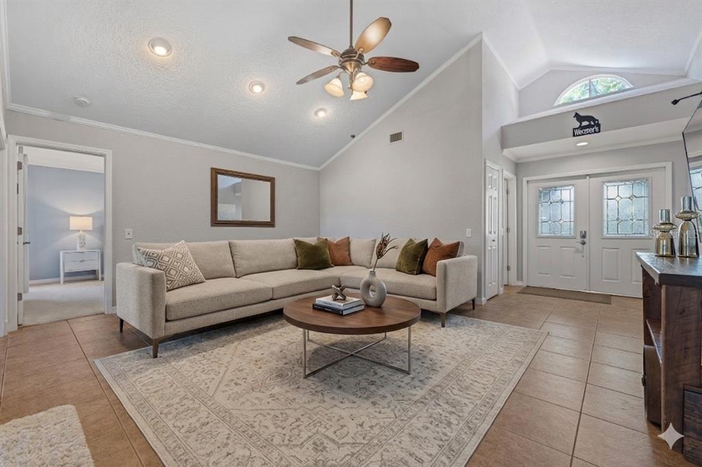 A living room with a sectional sofa, coffee table, vaulted ceiling, and tile flooring — 6349 PARSON BROWN DRIVE, ORLANDO, FL