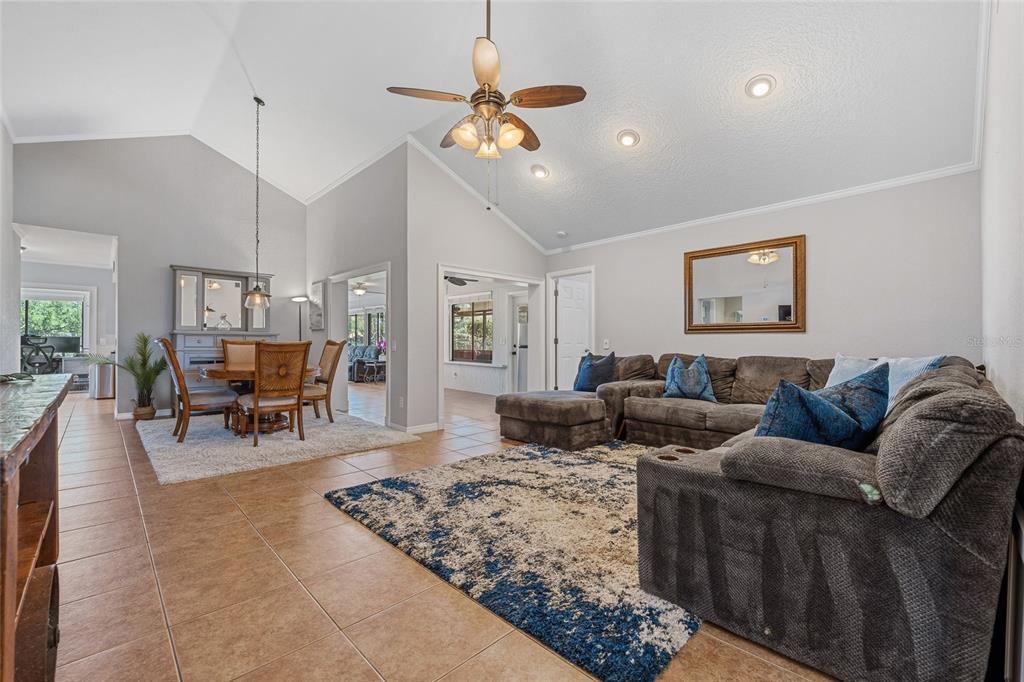 A living room and dining area with vaulted ceilings, tile floors, and a sectional sofa — 6349 PARSON BROWN DRIVE, ORLANDO, FL