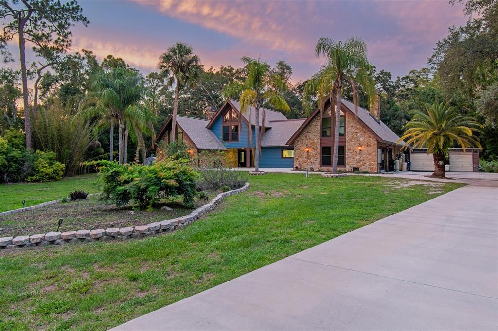 A two-story house with stone and blue siding features a concrete driveway and palm trees — 2120 MARQUIS COURT, NEW PORT RICHEY, FL