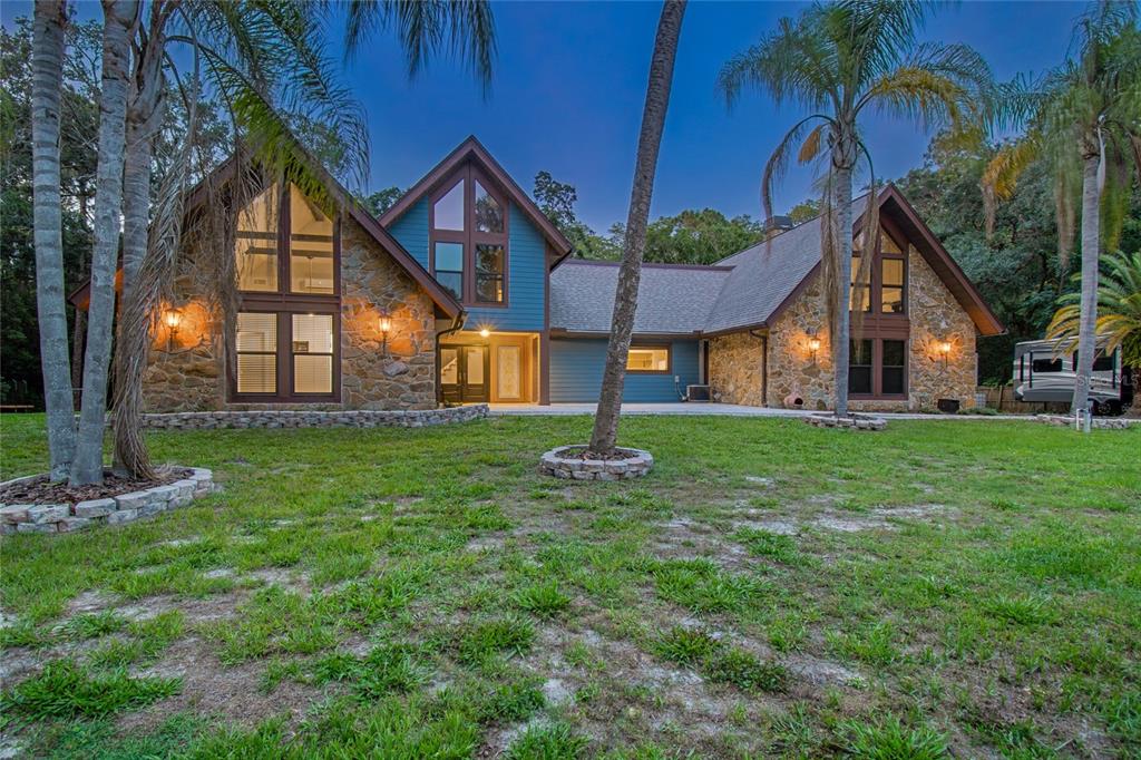 A two-story house with stone siding and blue accents stands behind a grassy lawn — 2120 MARQUIS COURT, NEW PORT RICHEY, FL
