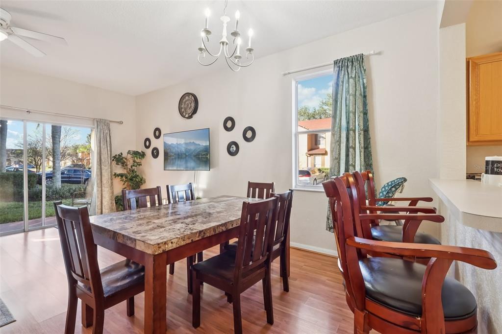 A dining room features a marble-topped table, dark wood chairs, a chandelier, and sliding doors — 353 TERRA LAGO STREET, DAVENPORT, FL