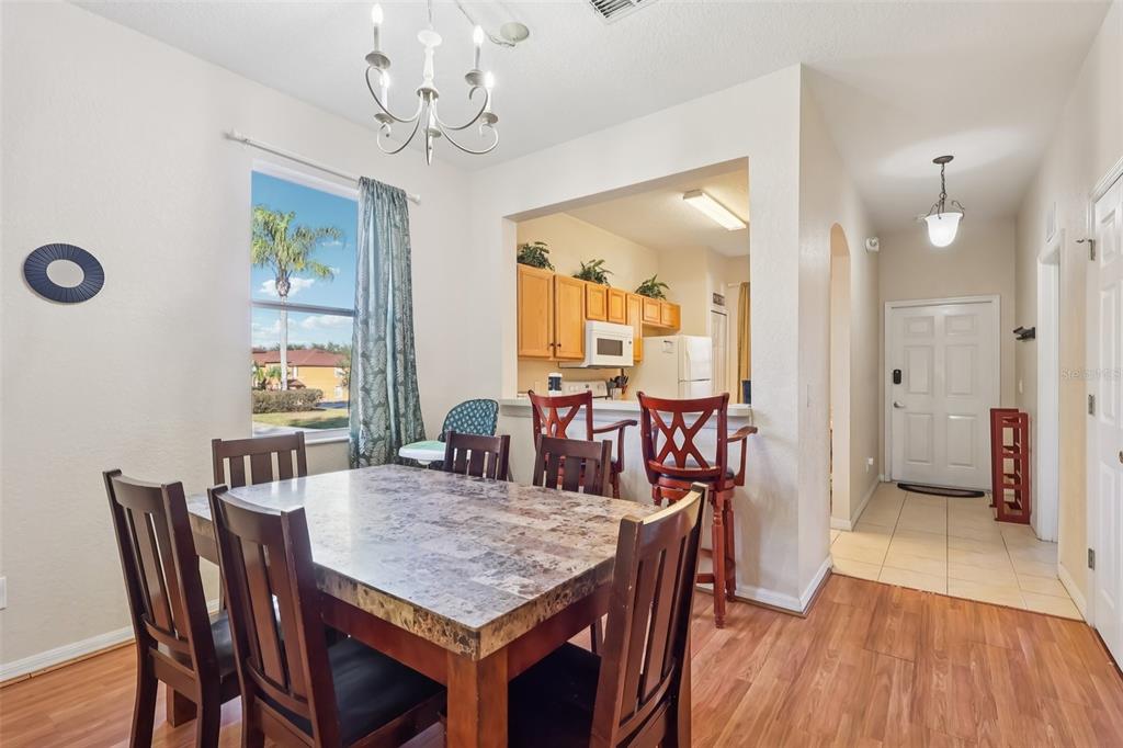 A dining area with a stone-topped table, wooden chairs, and a view into the kitchen — 353 TERRA LAGO STREET, DAVENPORT, FL