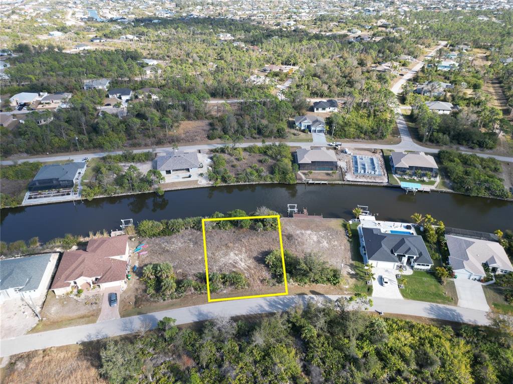 An aerial view shows a vacant waterfront lot outlined in yellow along a canal — 8258 SANTA CRUZ DRIVE, PORT CHARLOTTE, FL