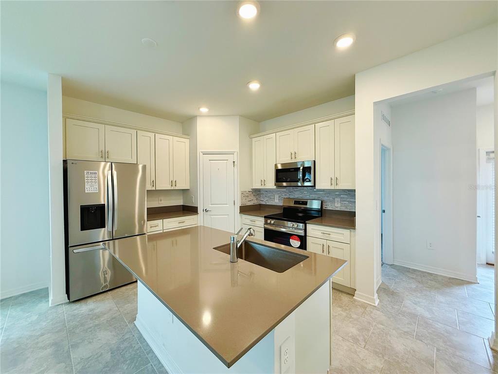 A kitchen with white cabinets, stainless steel appliances, a center island, and tile flooring — 4149 PINO STREET, APOPKA, FL