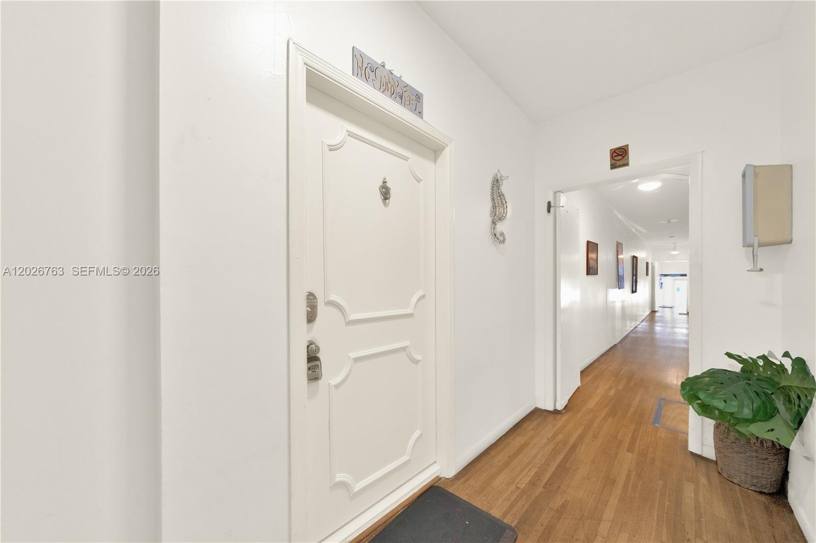 A white door with decorative molding opens into a hallway with hardwood flooring — 610 8th St # 102R, Miami Beach FL 33139, MIAMI BEACH, FL