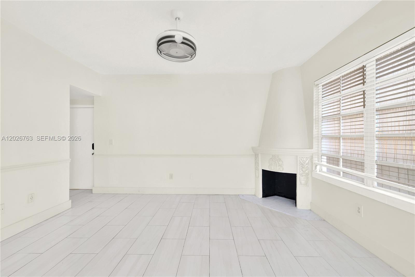 A bright room features white tile floors, a corner fireplace, and a ceiling light fixture — 610 8th St # 102R, Miami Beach FL 33139, MIAMI BEACH, FL