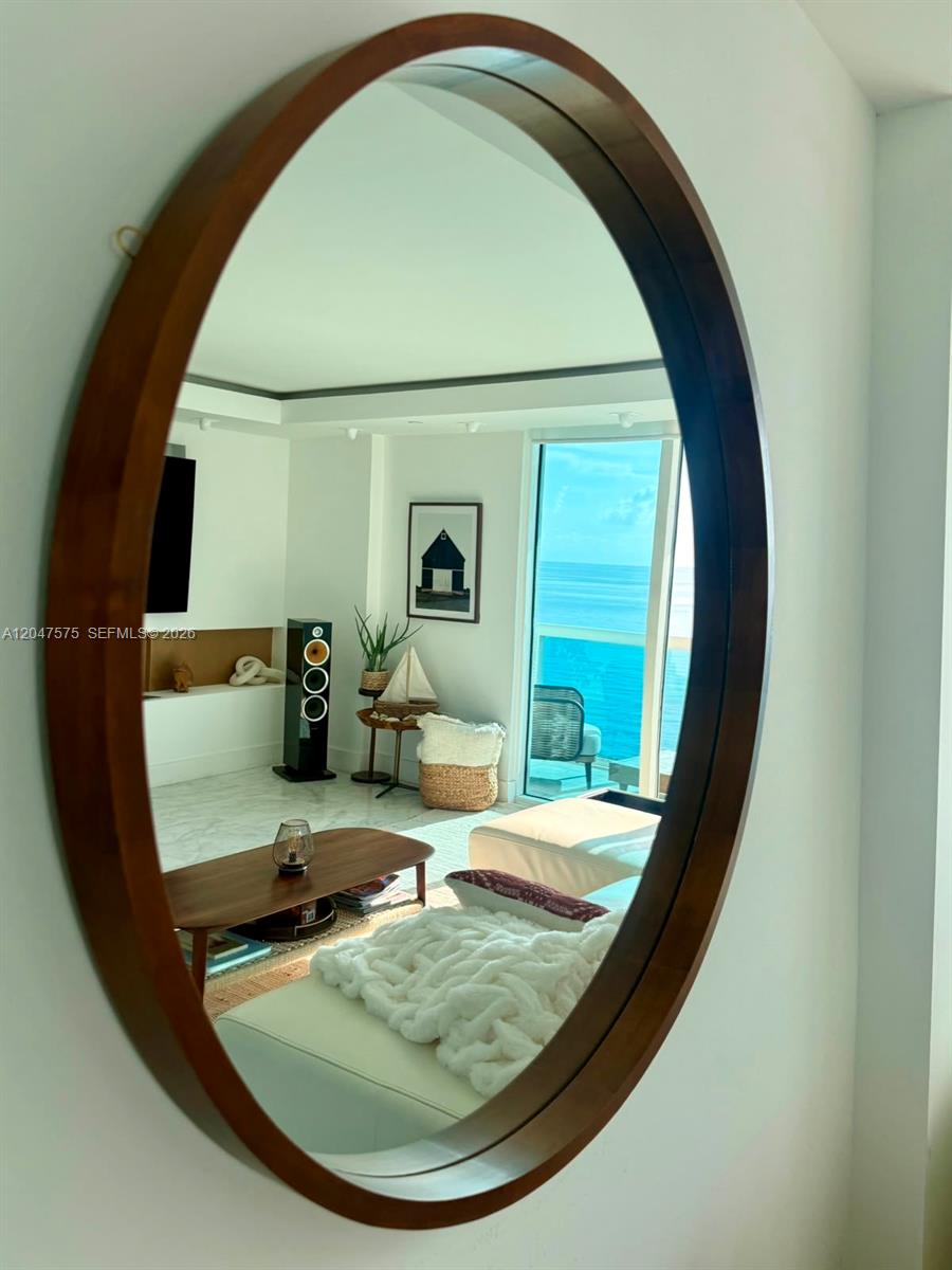 A large oval mirror reflects a bright living room with a view of the ocean — 9201 Collins Ave # 826, Surfside FL 33154, SURFSIDE, FL
