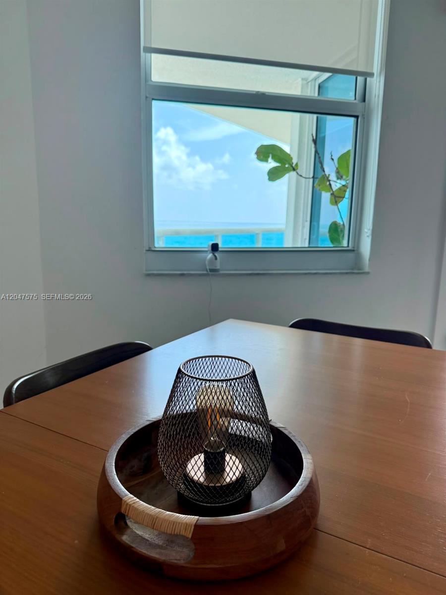 A dining table with a decorative lamp sits in front of a window overlooking the ocean — 9201 Collins Ave # 826, Surfside FL 33154, SURFSIDE, FL