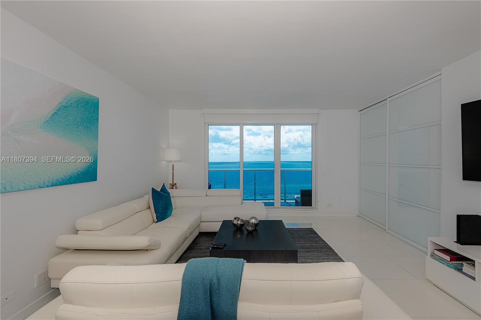 A living room features a white sectional sofa, a dark coffee table, and ocean views — 2301 Collins Ave # 1538, Miami Beach FL 33139, MIAMI BEACH, FL