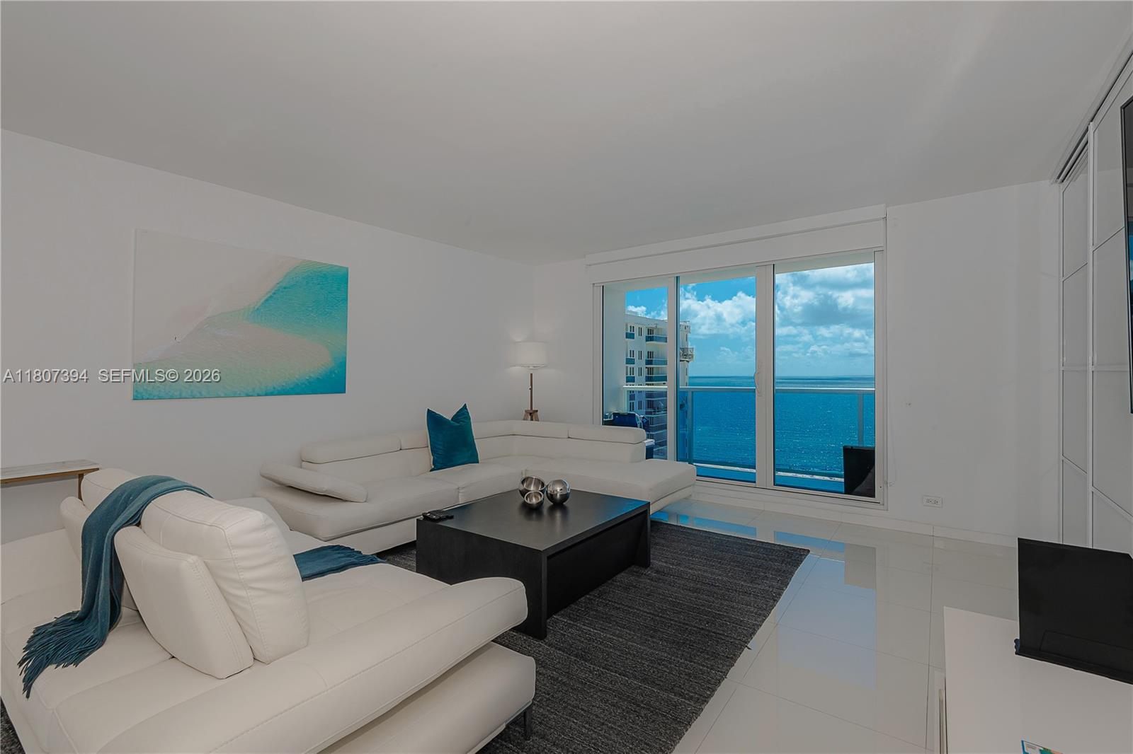 A living room features white leather sofas, a dark coffee table, and ocean views — 2301 Collins Ave # 1538, Miami Beach FL 33139, MIAMI BEACH, FL