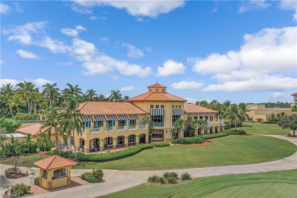 An exterior view of a large Mediterranean-style clubhouse with a tiled roof and palm trees — 2555 MARQUESA ROYALE LANE UNIT PH 302, NAPLES, FL