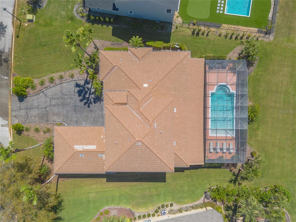 An aerial view shows a house with a tiled roof, a screened pool, and landscaping — 20 PROMENADE AT LIONSPAW, DAYTONA BEACH, FL