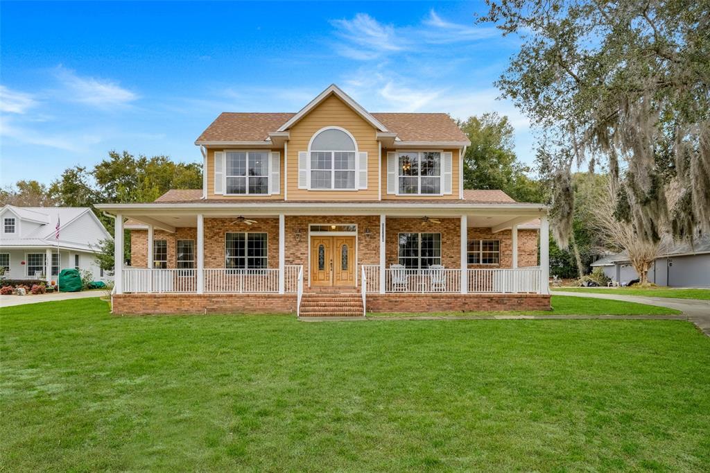 A two-story house with a brick ground floor, yellow siding, and a wide front porch — 10336 LAKE LOUISA ROAD, CLERMONT, FL
