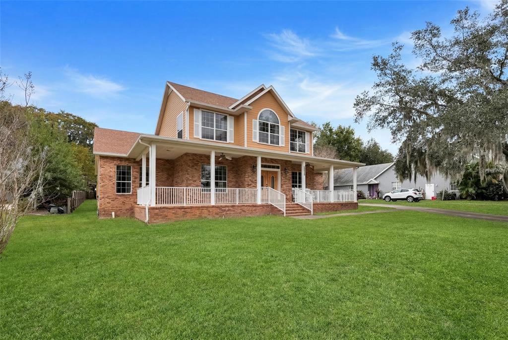 A two-story house with a brick lower level, yellow siding, and a large front porch — 10336 LAKE LOUISA ROAD, CLERMONT, FL