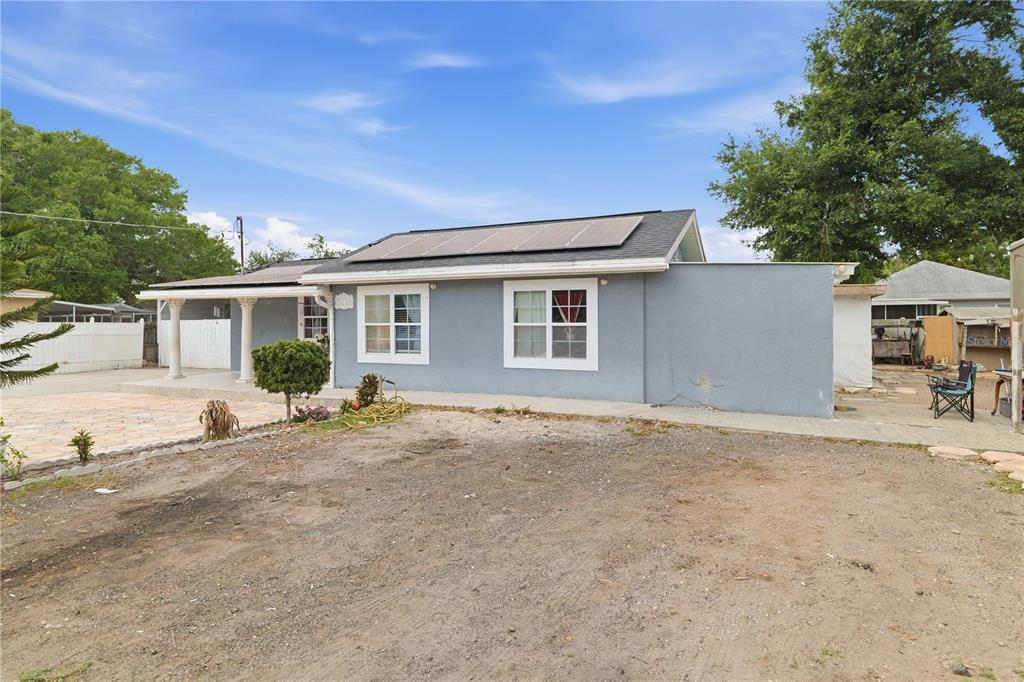 A single-story gray house with a covered porch, solar panels, and a dirt front yard — 1309 W ARCTIC STREET, TAMPA, FL