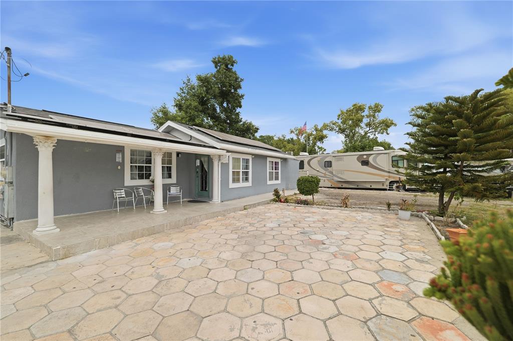 A gray house with a stone patio and a large RV parked in the yard — 1309 W ARCTIC STREET, TAMPA, FL