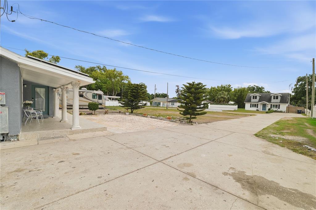 A concrete driveway leads to a house porch with columns and a parked recreational vehicle — 1309 W ARCTIC STREET, TAMPA, FL