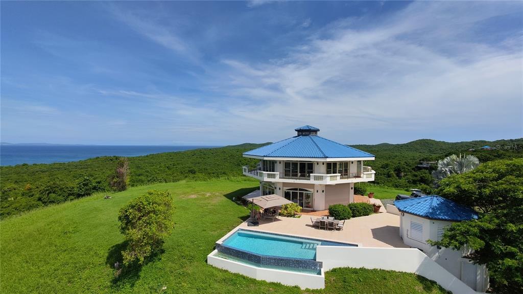 An aerial view of a multi-story, octagonal house with a blue roof, pool, and ocean views — 736 BRISAS DE JASMIN, VIEQUES, PR
