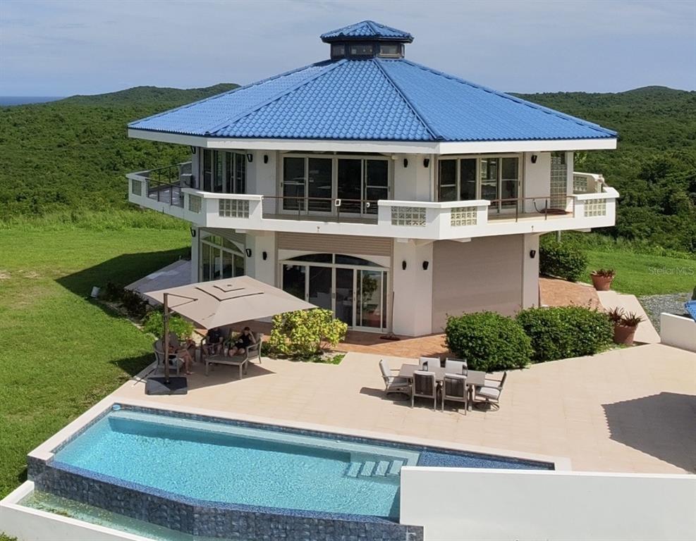 An elevated two-story house with a blue roof, wrap-around balcony, patio, and swimming pool — 736 BRISAS DE JASMIN, VIEQUES, PR