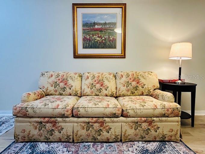 A floral patterned sofa sits beneath a framed landscape painting next to a side table — 100 PALM HARBOR PARKWAY UNIT 29, PALM COAST, FL
