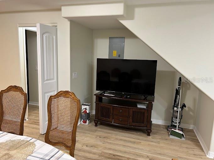 A television sits on a wooden stand beneath a staircase in a room with wood-look flooring — 100 PALM HARBOR PARKWAY UNIT 29, PALM COAST, FL