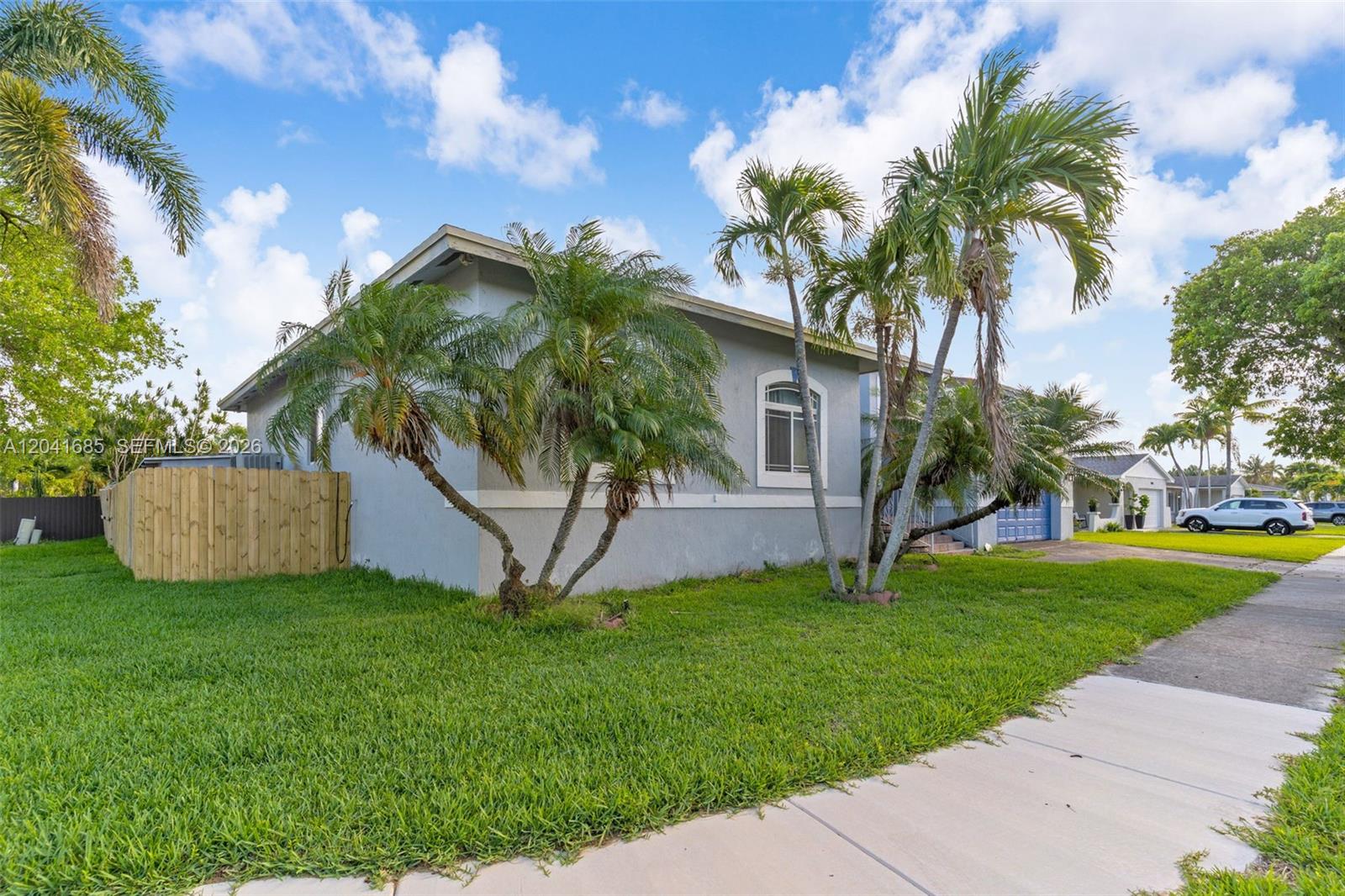 A single-story house with a gray exterior, palm trees, and a wooden fence — 7950 SW 196th Ter, Cutler Bay FL 33189, CUTLER BAY, FL
