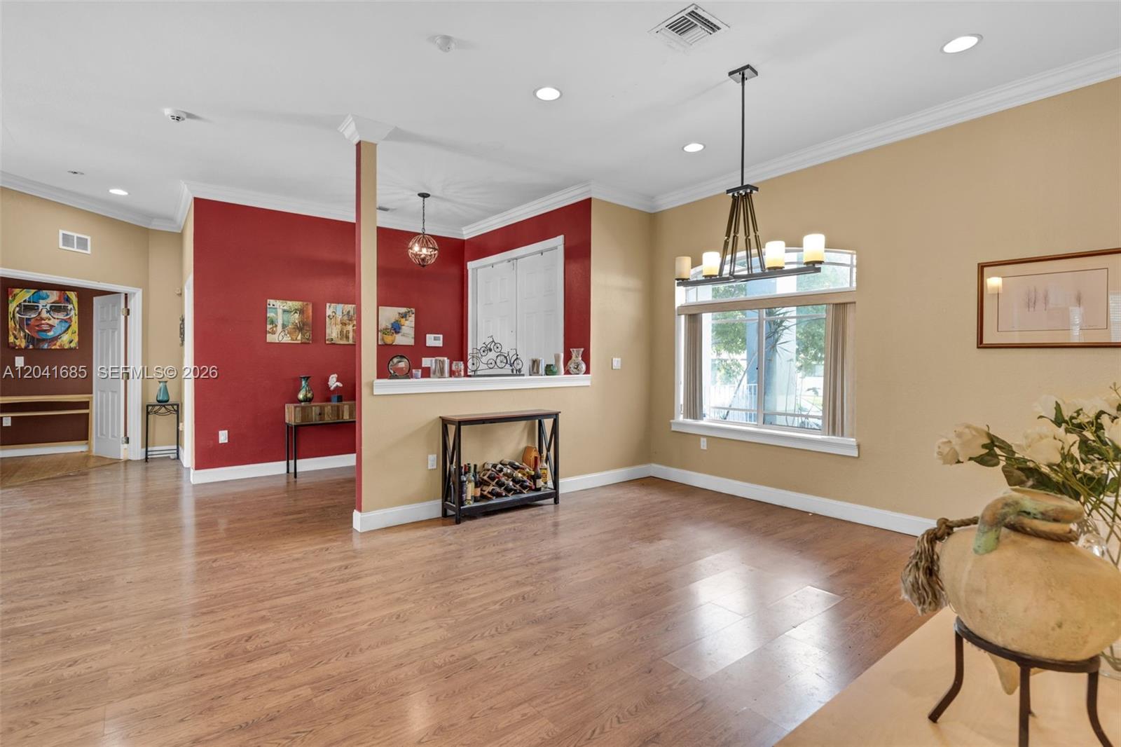 A dining room features wood flooring, a chandelier, and a partial wall with red paint — 7950 SW 196th Ter, Cutler Bay FL 33189, CUTLER BAY, FL