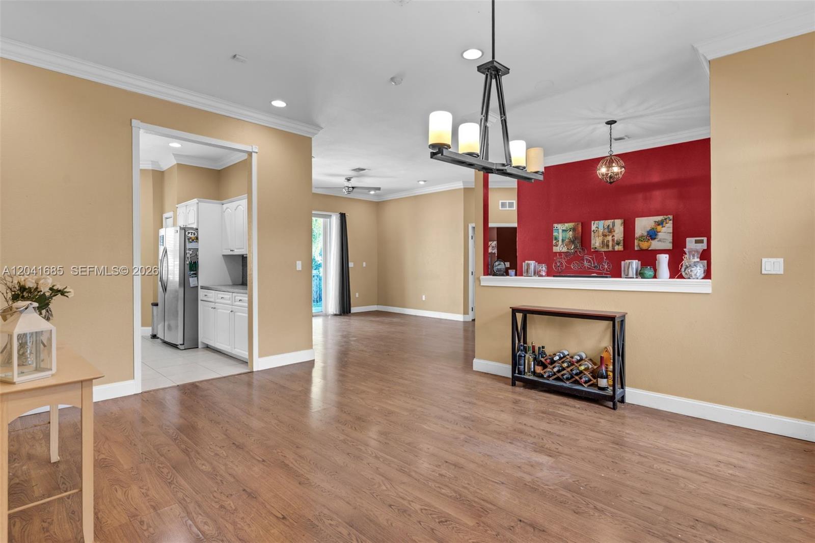 This open-concept living area features wood-look flooring, tan walls, and a red accent wall — 7950 SW 196th Ter, Cutler Bay FL 33189, CUTLER BAY, FL